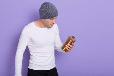 Indoor shot of handsome stylish man isolated over lilac background, wearing white casual shirt and...