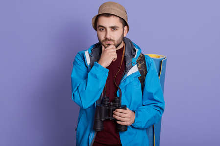 Young traveler caucasian man being confused, feels doubtful and unsure, posing against blue wall...