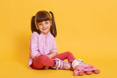 Smiling little kid with two funny ponytail looking directly at camera wit happy look, wearing...