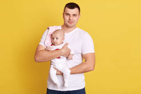 Attractive father holding his newborn baby in hands and looking directly at camera.の写真素材