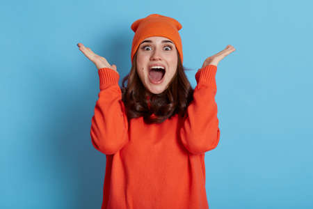 Woman expressing pleasant surprise, raises hands and looking at camera with positive shocked look,...