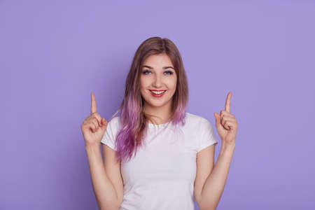 Woman with finger pointing up posing on purple background.の写真素材