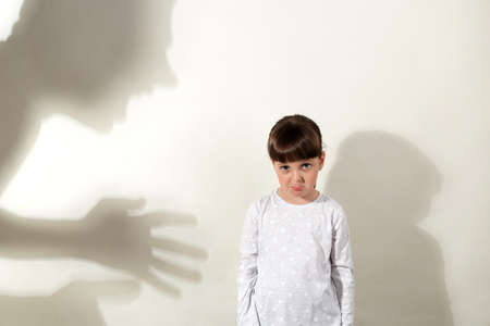 Shadow of aggressive human hits little girl, kid suffering from domestic violence, shadow silhouette...