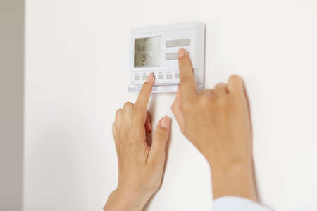 Unknown woman using smart home touch screen ai technology connected appliances device on wall...