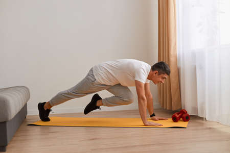 Sport, fitness and healthy lifestyle. Young strong attractive man doing running plank exercise at...