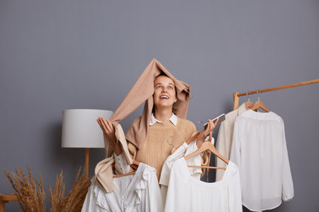 Lovely positive extremely happy woman fashion stylist posing in designer store or wardrobe with trendy outfit on rack, expressing happiness, sold all items from her boutique online.の写真素材