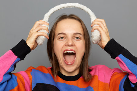 Portrait of joyful cheerful winsome attractive woman with brown hair wearing colorful jumper posing...