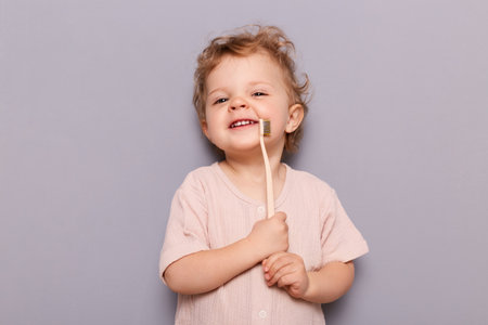 Image of satisfied girl kid holding toothbrush, taking care of her teeth health from early...