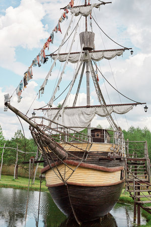 Big ship in port on bank of river or lake near the forest sightseeing sailboat with sails traveling...
