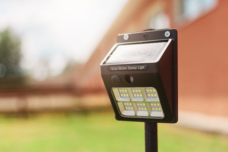 Outdoor garden lamp on the grass, light sensor in te yard with building on background.の写真素材