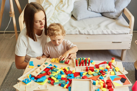 creative learning game. Playful parent-child interaction. teacher or mother playing with baby with logical toys at home interiorの写真素材