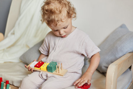wooden construction set. Active toddler play. creative learning games. Cognitive skill development. Little blonde baby girl palying with wooden sorter toys at home interior.の写真素材