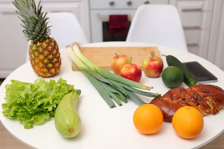 Home cooking on domestic kitchen table adorned with a variety of organic ingredients including zucchini pineapple orange lettuce apple leek ready for delicious and nutritious preparation.の写真素材
