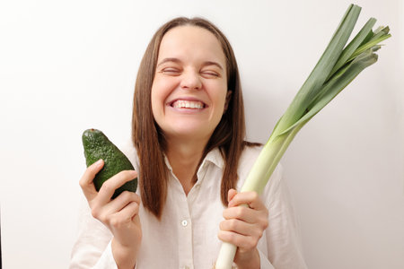 Healthy eating joy. Extremely happy joyful cheerful Caucasian woman holding green leek and avocado...