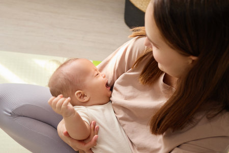 Top view of mother embracing her crying baby boy trying to calm him down while he pouting sadly...
