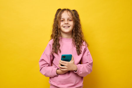 Adorable schoolgirl with curly hair wearing fashionable sweatshirt smiling brightly enjoying her...