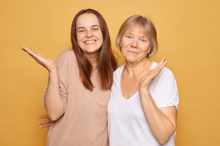 Two women stand side by side, exchanging smiles and playful gestures, highlighting their close relationship in a warm and lively environment.の写真素材