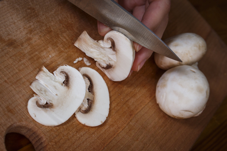 A girl is cutting mushrooms on a cutting boardの写真素材
