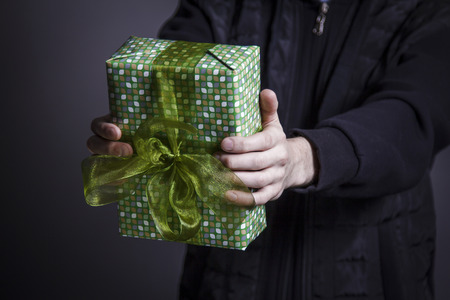 The guy is holding a box with a gift and a green bowの写真素材