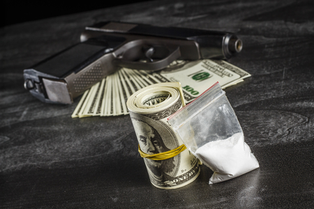 Drugs in a plastic bag with a bunch of dollars and a gunの写真素材