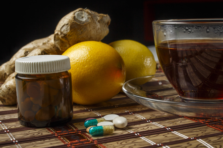 A pile of pills with a cup of tea, lemon and thermometerの写真素材