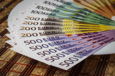 A pile of euros on a white plate on the table