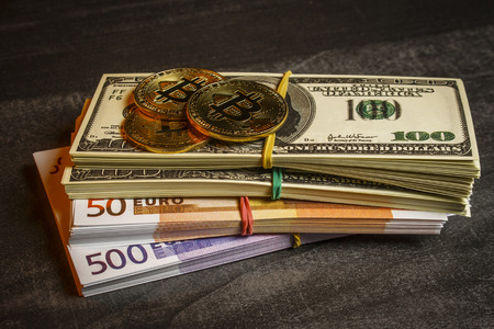 Coins in the form of bitcoins are on packs of dollars and eurosの写真素材