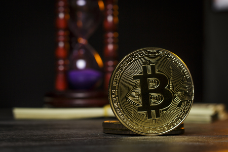 Hourglass with wad of dollars and gold coins in the form of bitcoinの写真素材