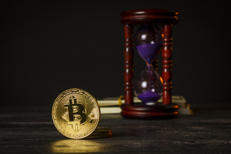 Hourglass with wad of dollars and gold coins in the form of bitcoinの写真素材