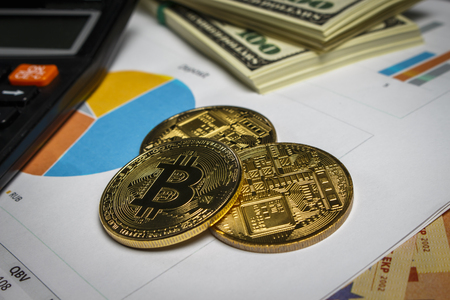 Bitcoin gold coins with a calculator and packs of dollarsの写真素材