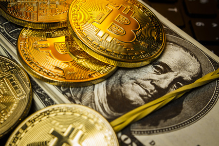 Gold coins cryptocurrency lie with packs of dollars on the laptop keyboard