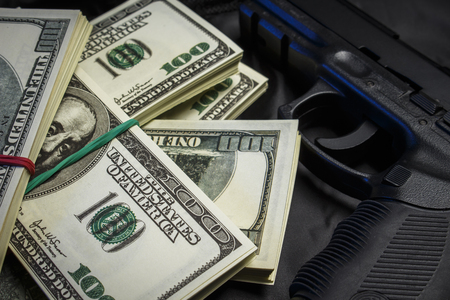 Bundle of dollars with a gun in a black bagの写真素材