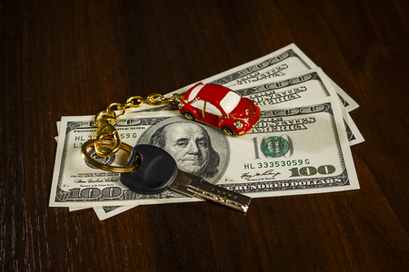 Key with a keychain in the form of a car on dollarsの写真素材