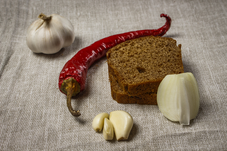 Bread, pepper, garlic and onion on burlapの写真素材