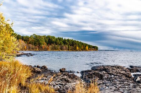 beautiful autumn landscape with clouds, forest and lakeの写真素材