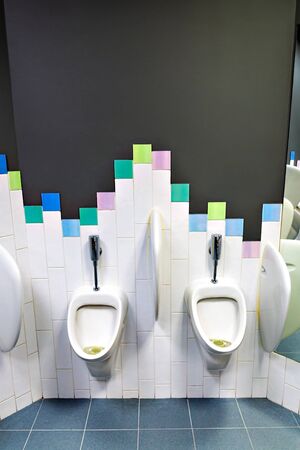 two children's urinals located at different heights in a public toiletの写真素材