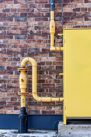 yellow gas pipes on a brick wall backgroundの写真素材