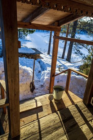 a bucket of water on the porch of a village house. winter village landscapeの写真素材