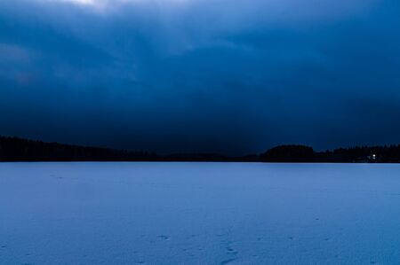 night winter landscape with a frozen lake and sky tightened cloudsの写真素材