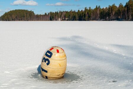 a buoy frozen in the lake's ice. winter sunny landscapeの写真素材