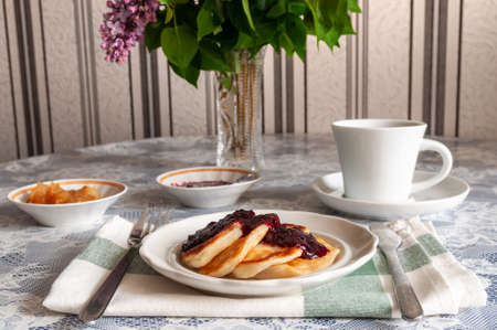 still life with breakfast at the round table. On the table is a cup of tea and pancakes with jam.の写真素材
