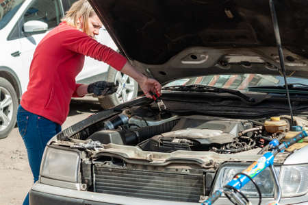 Petrozavodsk, Russia - 24 May 2020. A young woman at the open bonnet of a car is trying to fix the malfunctionのeditorial素材
