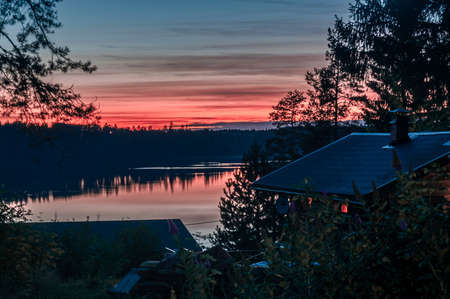 evening landscape with sunset skies, forest and rooftopsの写真素材