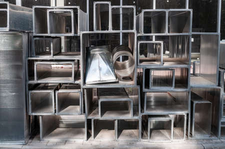 metal structures of various geometric shapes stacked together. Ventilation elements and metal beams stacked on construction siteの写真素材