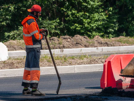 Petrozavodsk, Russia - 21 June 2020. Road worker in uniform thoughtfully holds a shovelのeditorial素材