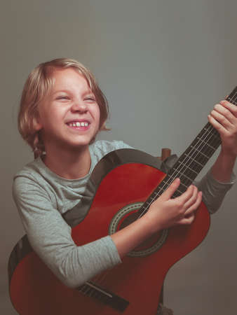 little girl with guitar on gray background. High quality photo