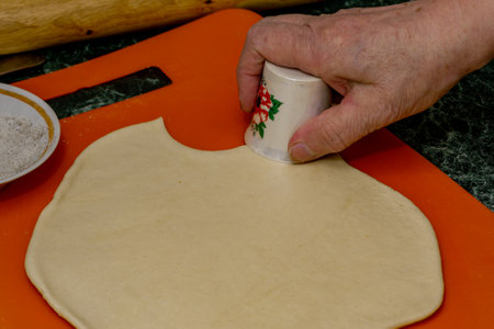 Woman cuts circles from the dough using a stack