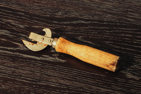 old dirty can opener on a wooden backgroundの写真素材