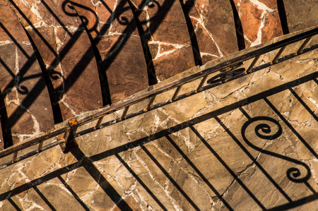 abstract background with shadows from the forged fence and stone steps