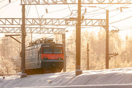 winter landscape with a locomotive in the rays of the setting sun